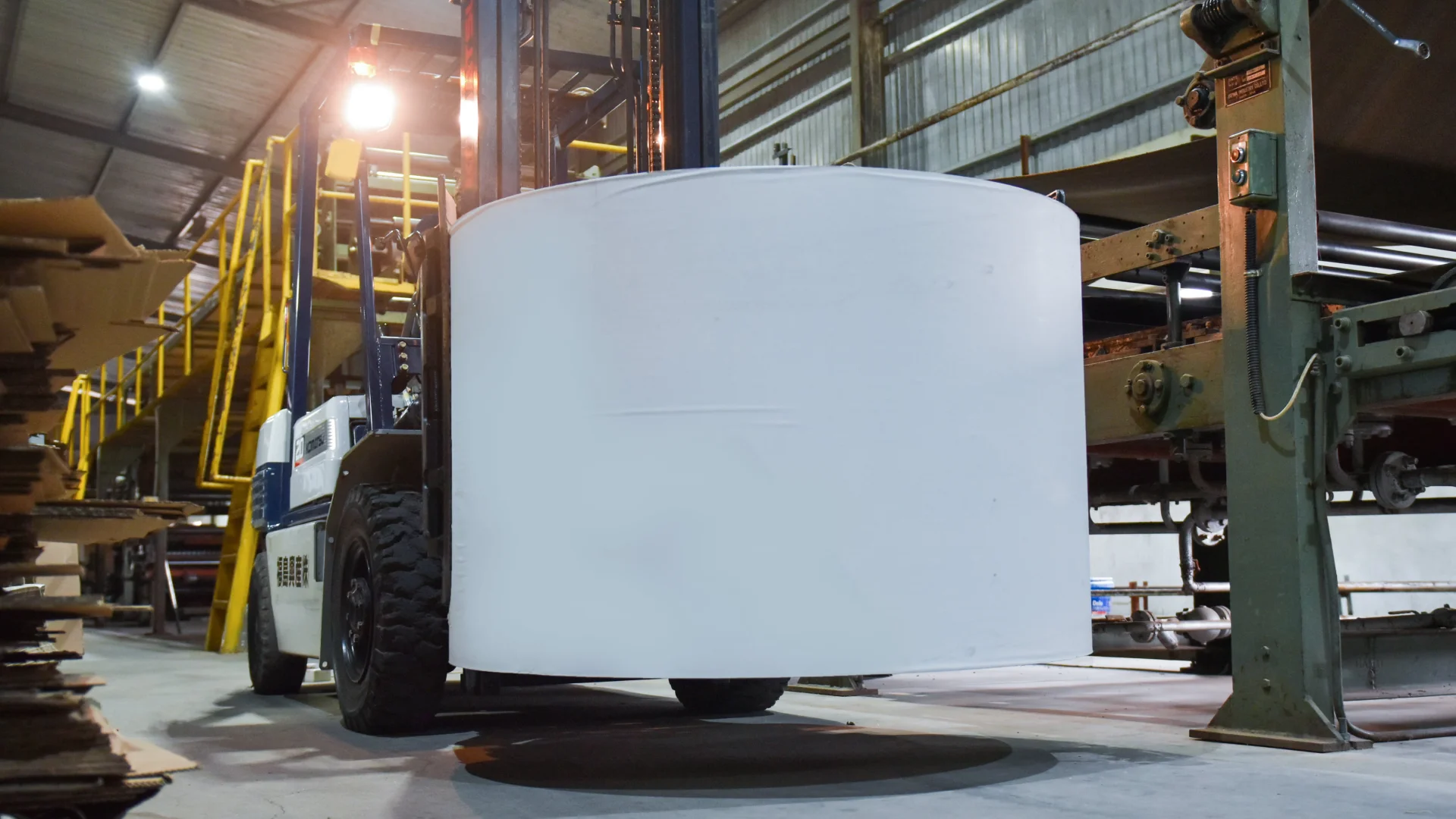 Forklift moves a large roll of paper at EZI factory