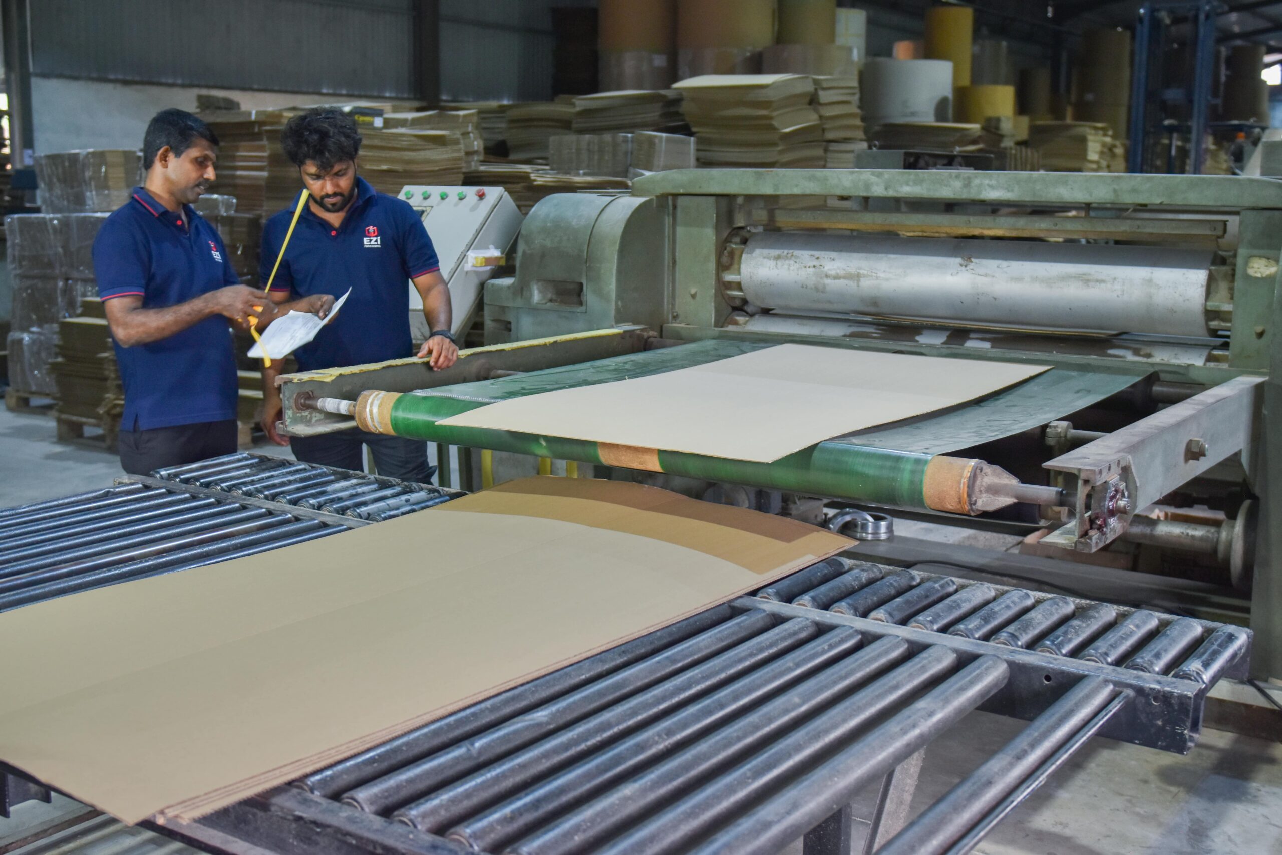 Two members working with a corrugated box manufacturing machine at EZI Packaging