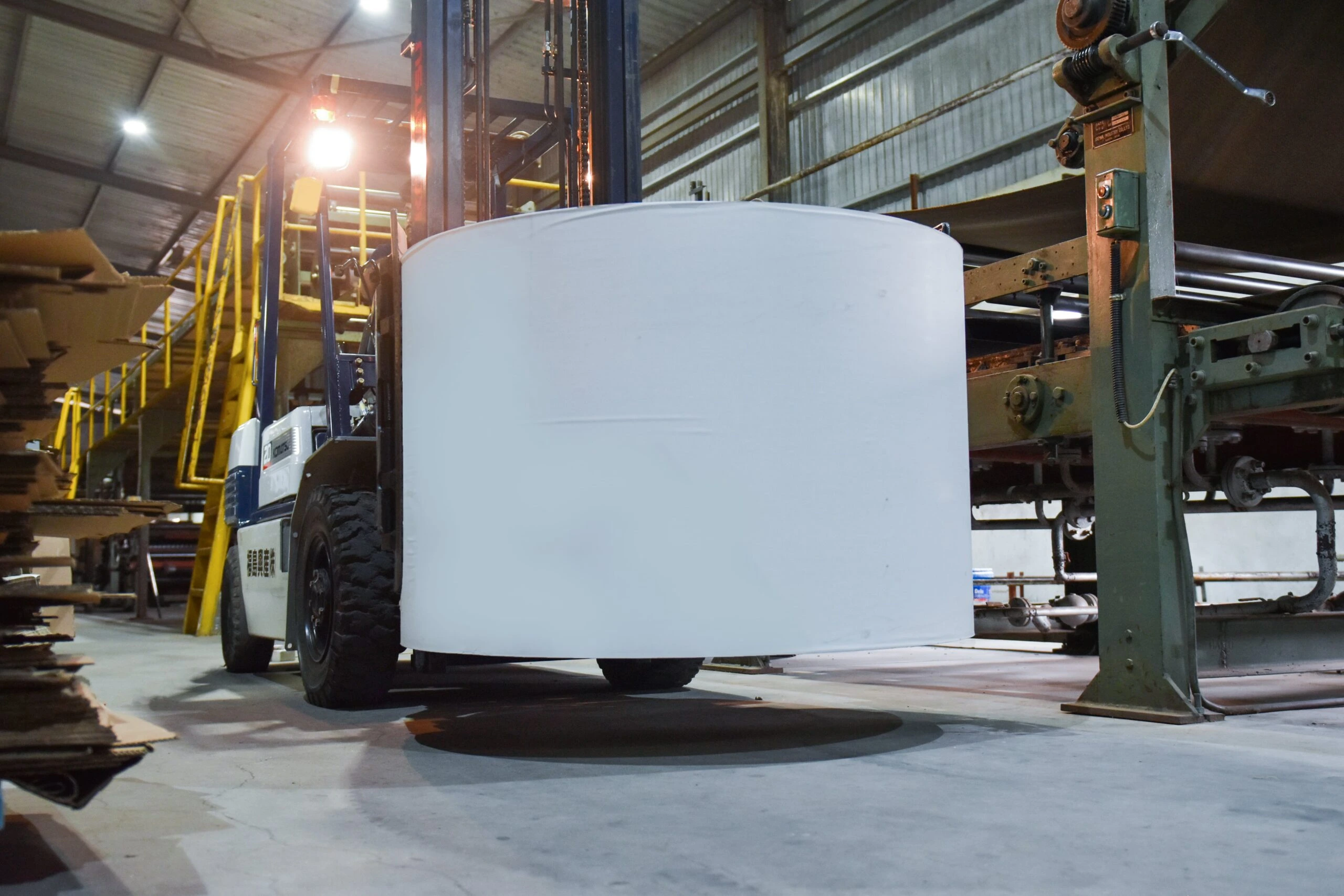 Forklift moves a large roll of paper at EZI factory