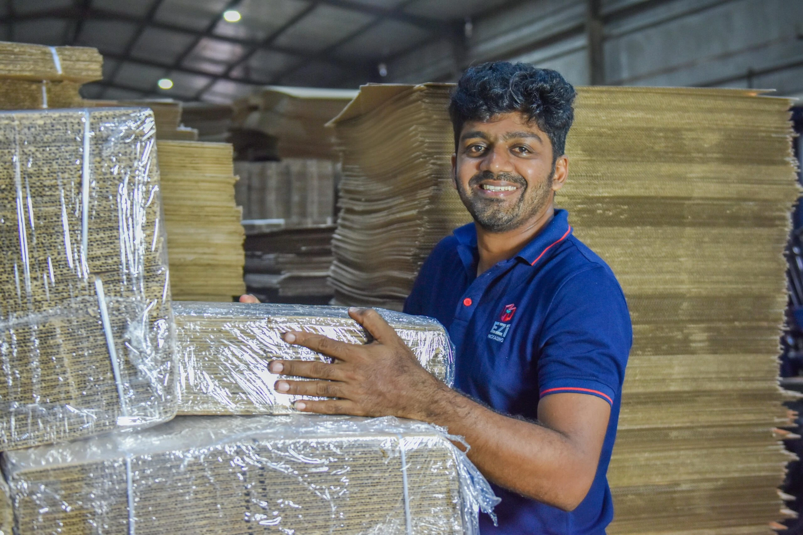 A EZI team member holding cardboard boxes in the factory