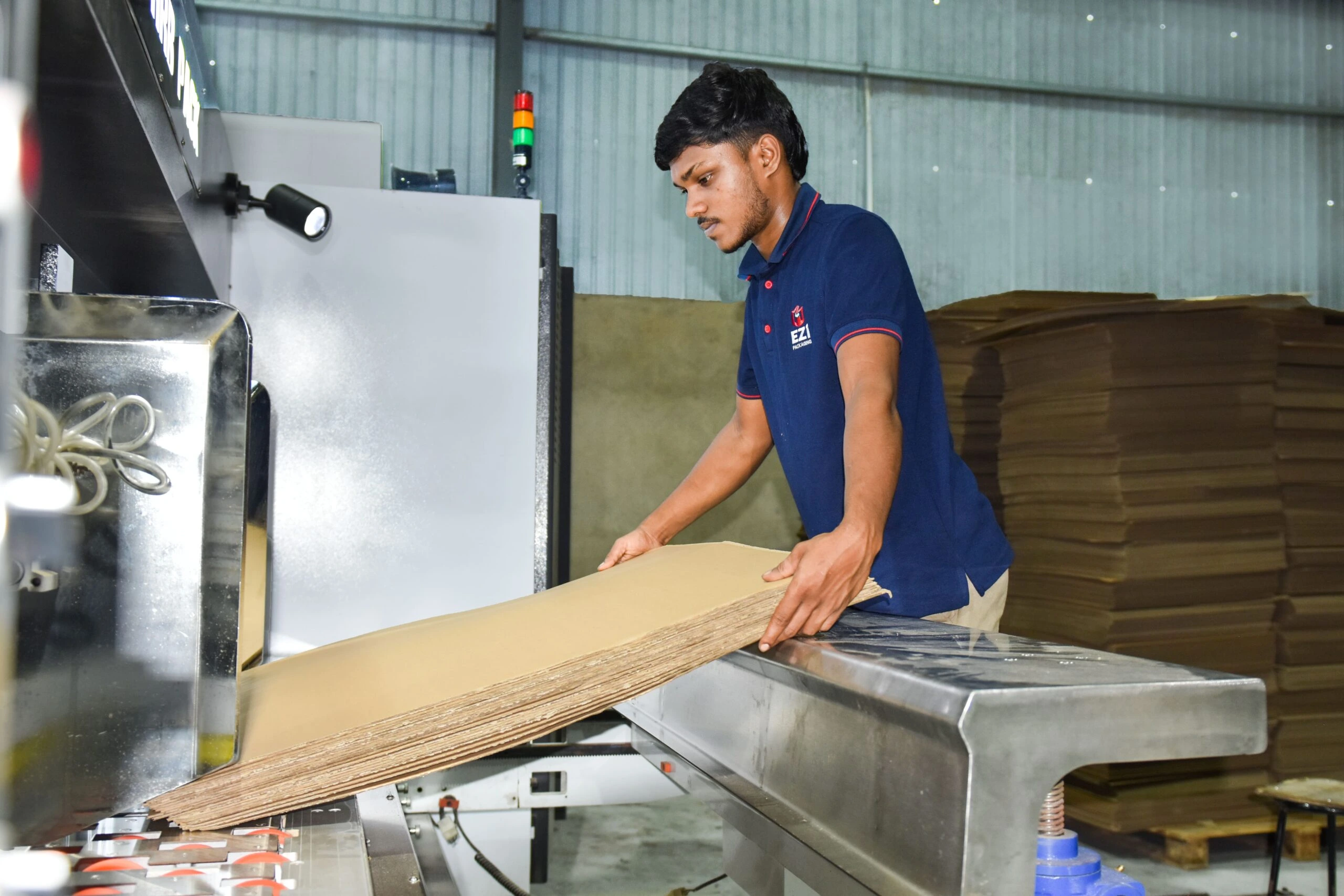 Factory operator feeding corrugated cardboard sheets into packaging machine at EZI Packaging Sri Lanka