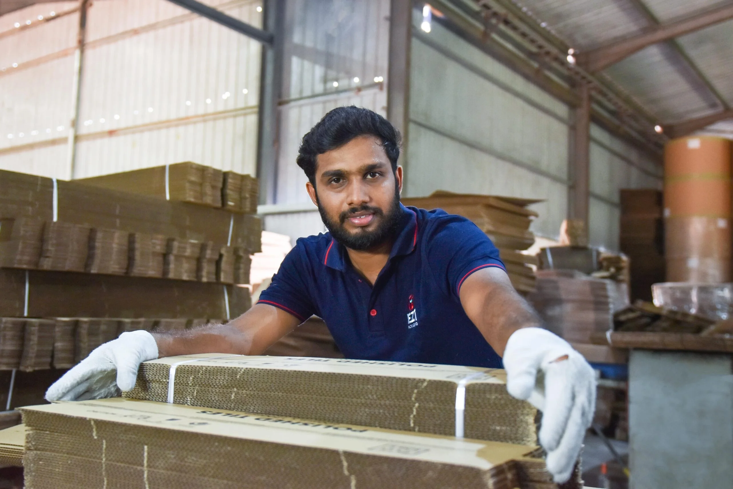 Worker handling stacked corrugated cardboard packaging boxes at EZI Packaging Sri Lanka factory